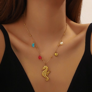 Close-up of a gold seahorse necklace with blue tassels, pearls, and shell charms on a model