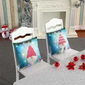 Detail of Christmas gnome pillow covers with LED lights and 3D faux fur beards on white chairs