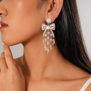 Detailed view of silver bow earrings with rhinestone tassels and teardrop crystal pendants