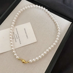 Collana di perle vintage francese con chiusura magnetica dorata su sfondo neutro