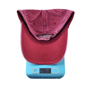 Detail of burgundy washed cotton baseball cap weighing 75g on a digital scale