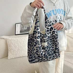 Detail of leopard print canvas tote bag featuring stitched brand tag and beige lining