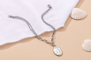Silver double layer stainless steel necklace with oval Virgin Mary coin pendant on beige background