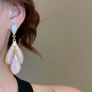 Close-up of a large gold petal drop earring with pink and blue iridescent shell inlay