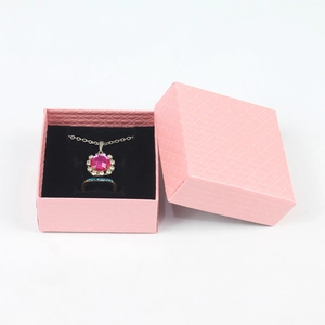 Close-up of pink jewelry gift box with black velvet lining, necklace and ring inside