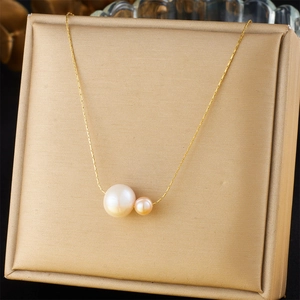 Detail of elegant gold chain necklace featuring asymmetric white and pink pearls