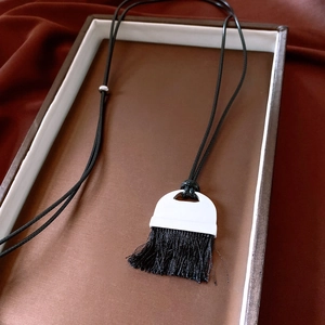Close-up of vintage leather tassel necklace with geometric pendant and woven rope