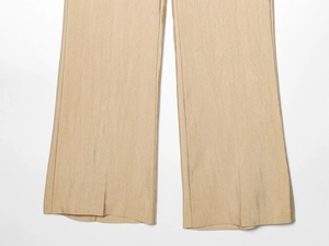 Detail van de goudkleurige wijde broek met een metallic satijnglans en soepele valling