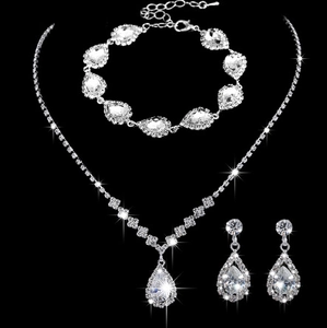Macro shot of silver bridal jewelry set featuring teardrop crystals on black background