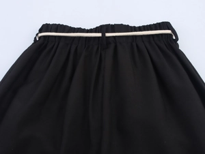 Dettaglio dei pantaloni neri da donna con vita elastica e cintura in corda intrecciata
