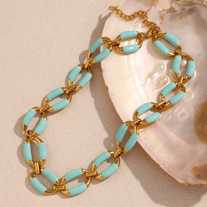 Detailed macro view of 18K gold plated necklace with green enamel links on a seashell background