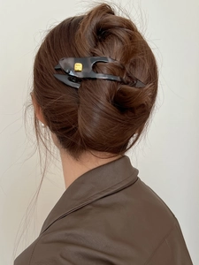 Detail of tortoise shell hairpin with fashion buckle on model's bun hairstyle