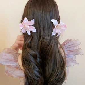 Detail of pink and white gradient fabric lily flower hair clips on brown wavy hair