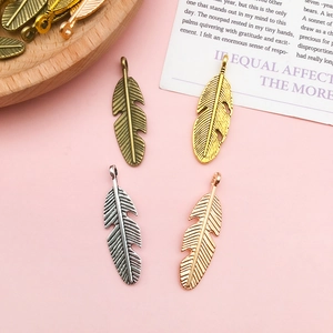 Macro shot of feather-shaped alloy pendants in bronze, gold, silver, and rose gold finish