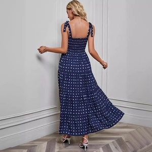 Back view of a blue polka dot backless maxi dress with a tiered skirt and tie straps