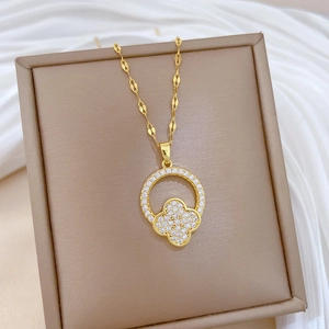Detail of gold clover necklace with small round diamonds on beige jewelry box display