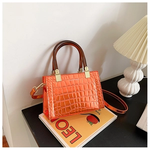 Detail of bright orange faux leather bag with crocodile texture and resin handle