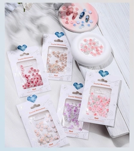 Detail of assorted resin flower nail charms and rhinestones in professional packaging
