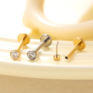 Orecchini labret in titanio con retro piatto in oro e argento su sfondo sfumato morbido