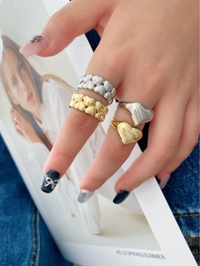 Close-up of elegant double-layered gold and silver heart-shaped chain rings on a hand
