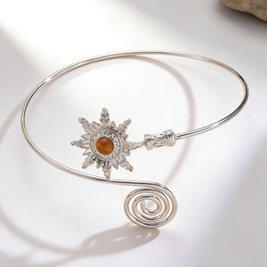 Detail of silver arm cuff with sunburst charm and amber stone in bohemian style