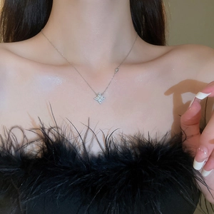 Silver star pendant necklace worn by a model in a black feathered outfit for style
