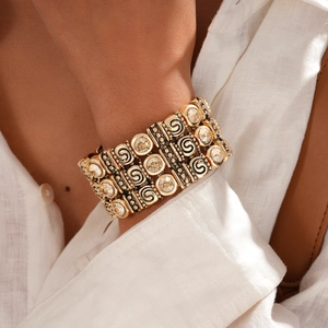 Detailed macro view of vintage gold multi-layer bracelet with crystal inlays and spiral motifs