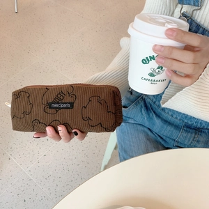 Detailed macro view of a brown corduroy pencil case featuring a hand-drawn cartoon bear