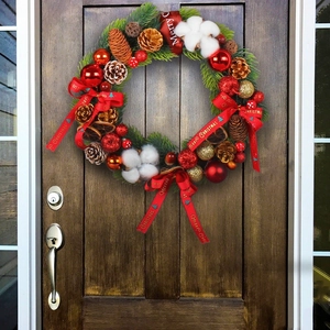 Christmas wreath with pine cones and gold balls on wooden door with Merry Christmas ribbon