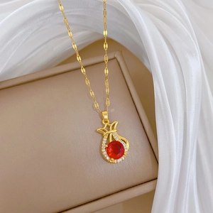Detailaufnahme der goldenen Glücksbeutel-Halskette mit rotem Stein auf Schmuckkästchen