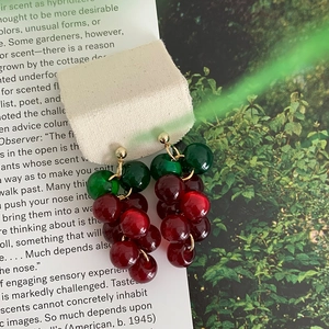 Close-up of realistic red grape resin tassel earrings with elegant gold-tone studs.