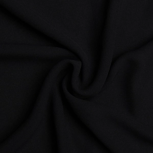 Dettaglio della trama del tessuto nero e dei morbidi drappeggi di questo abito elegante