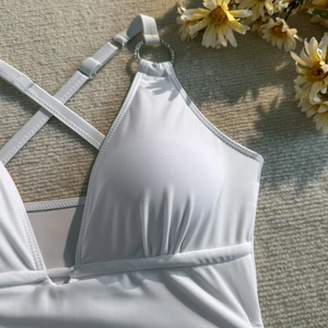 Détail d'un maillot de bain blanc avec licou, anneau en argent et texture de poitrine plissée