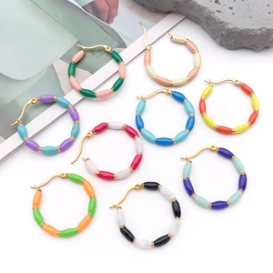 Macro shot of colorful bamboo-shaped enamel hoop earrings on grey textured stones