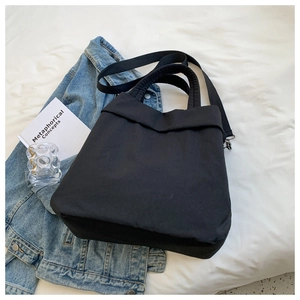 Detail of a black nylon tote bag showing its soft texture and dual carrying straps