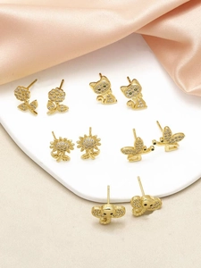 Detailed view of gold earrings set with zircon featuring cat, flower and elephant designs