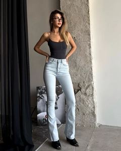 Detail of high-waisted flared jeans with light blue wash and slim fit denim texture