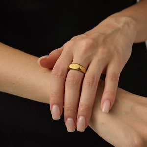 Gros plan d'une bague chevalière ovale minimaliste en acier inoxydable doré sur un mannequin