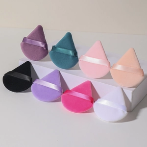 Primer plano de borlas de maquillaje de terciopelo en forma de gota con cinta seda
