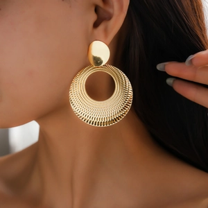 Close-up of golden textured hollow circle earrings worn by model for a stylish metal look