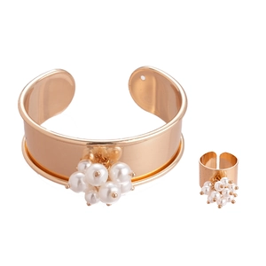 Elegant gold metal jewelry set with cluster pearls including an open cuff and ring