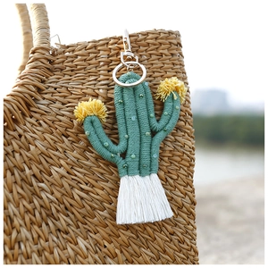 Close-up of handmade beaded cactus keychain with white tassel on a straw bag