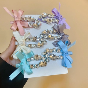 Détail de six barrettes à nœuds en satin de couleurs avec strass sur cartes de support