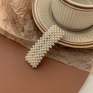 Detailed view of rectangle pearl hair clip with gold alloy base on a vintage background