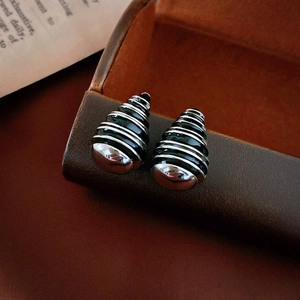 Macro detail of retro shell-shaped earrings with black enamel and silver needles