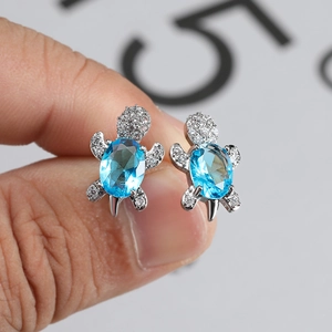 Silver turtle stud earrings featuring blue oval gemstone and white cubic zirconia accents