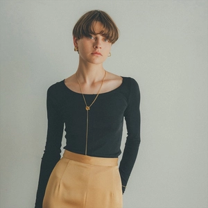 Model wearing gold Y-pendant layered necklace with a black slim-fit round-neck sweater