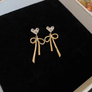 Close-up of golden bow earrings with heart crystals in a black velvet jewelry box