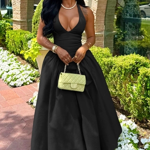 Close-up detail of a black deep V-neck halter evening dress on a model in an outdoor garden