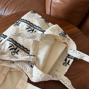 Detail of French vintage lace embroidery and floral pattern on cream cotton tote bag